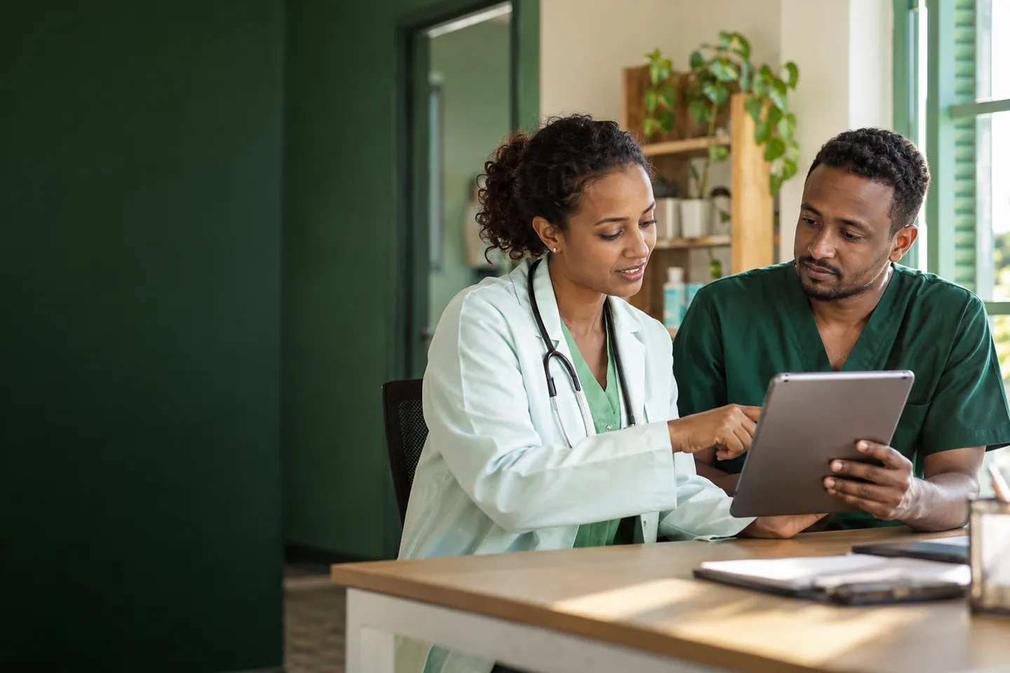 A doctor and a nurse review a tablet together in their clinic