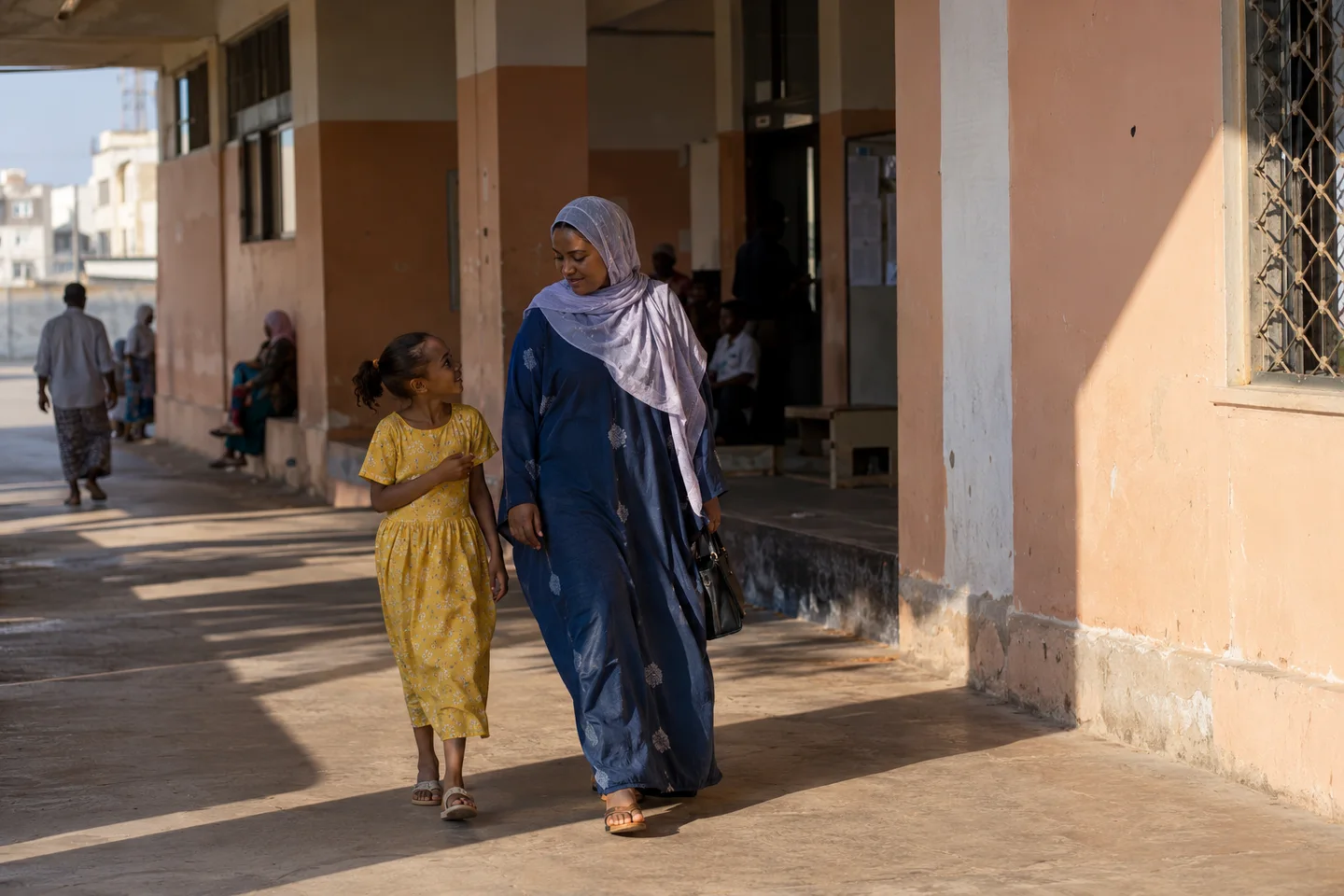 Une mère et sa fille marchent ensemble sous une arcade à Djibouti
