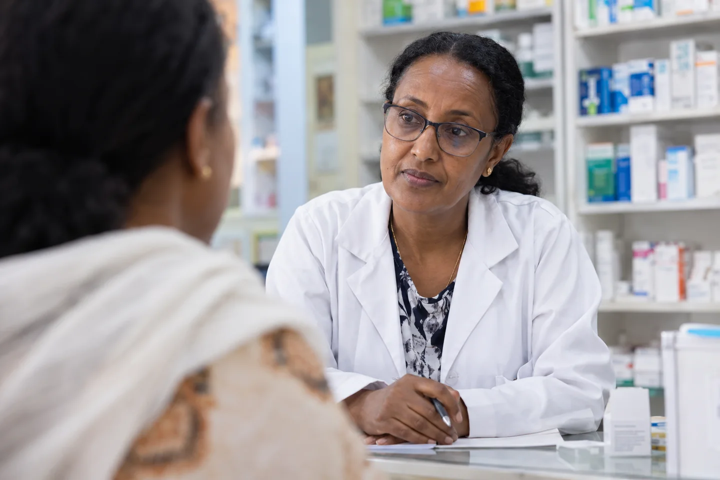 Une pharmacienne écoute une cliente au comptoir de sa pharmacie à Addis-Abeba
